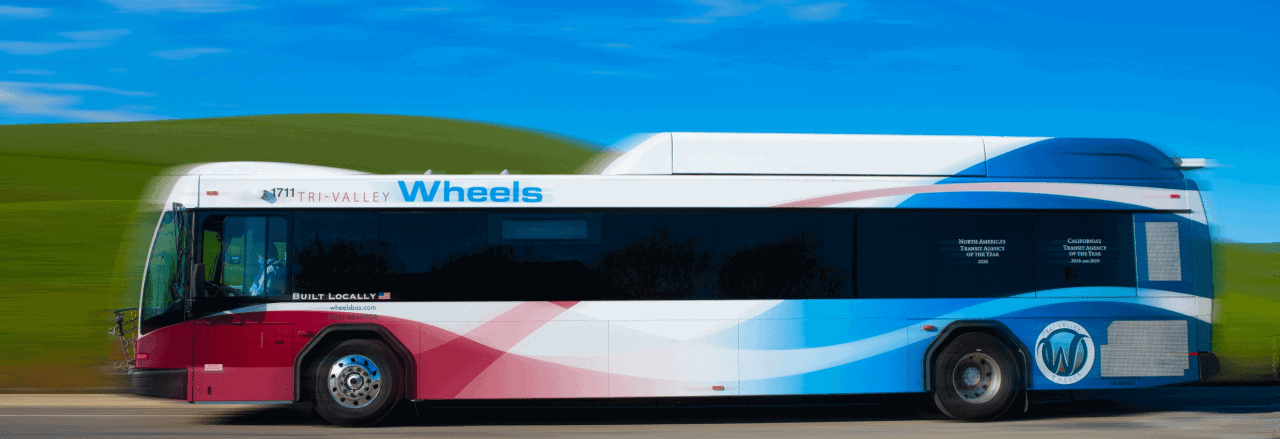 Bus in motion against green hills and blue sky